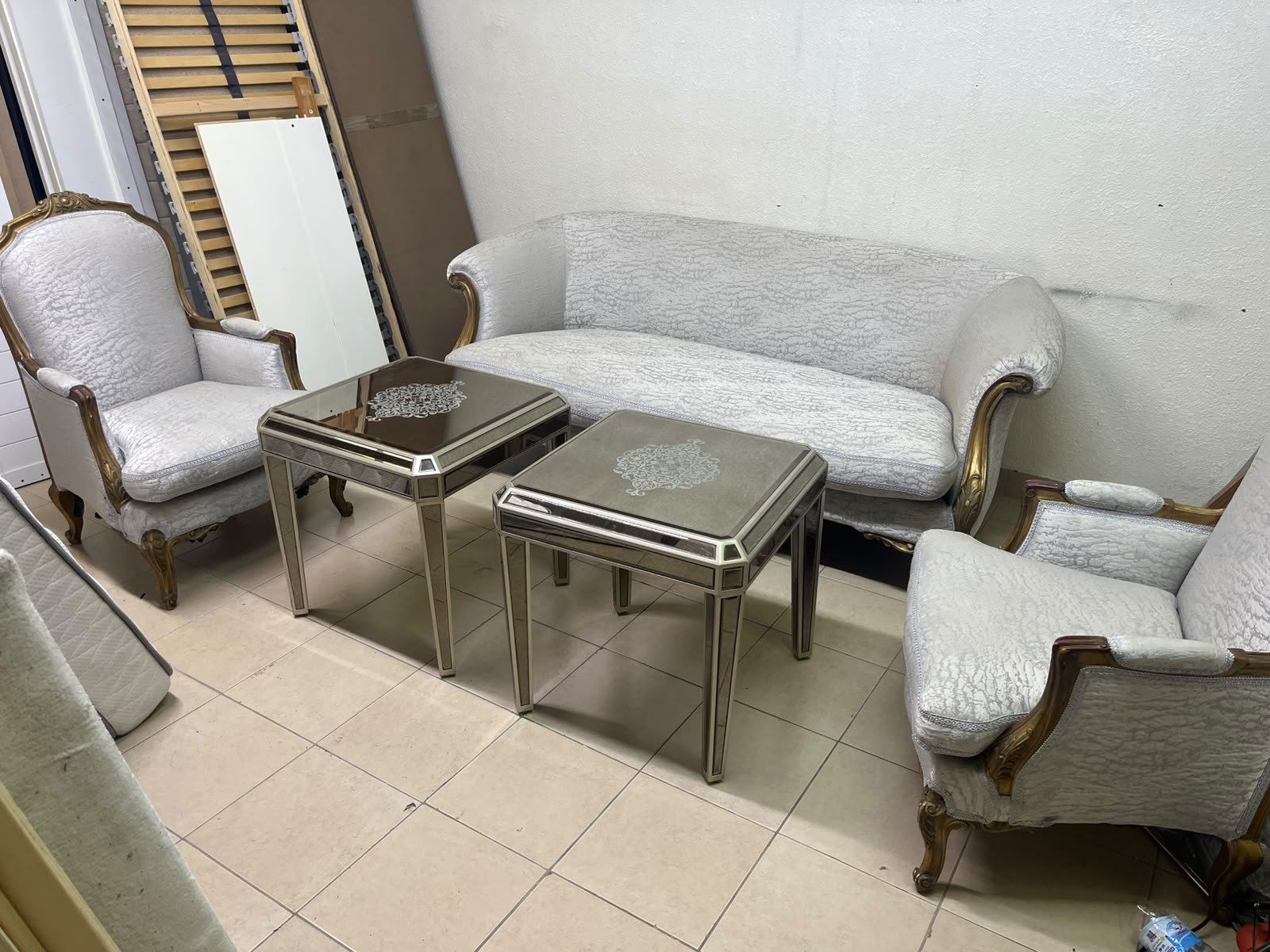 A light-colored, upholstered classic living room set featuring a sofa and armchairs with carved wooden frames, along with two matching mirrored side tables. - Image 2