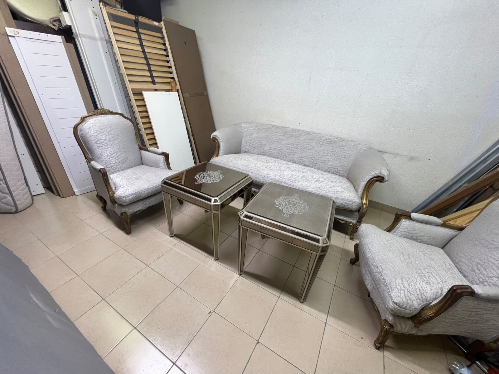 A light-colored, upholstered classic living room set featuring a sofa and armchairs with carved wooden frames, along with two matching mirrored side tables. - Image 7