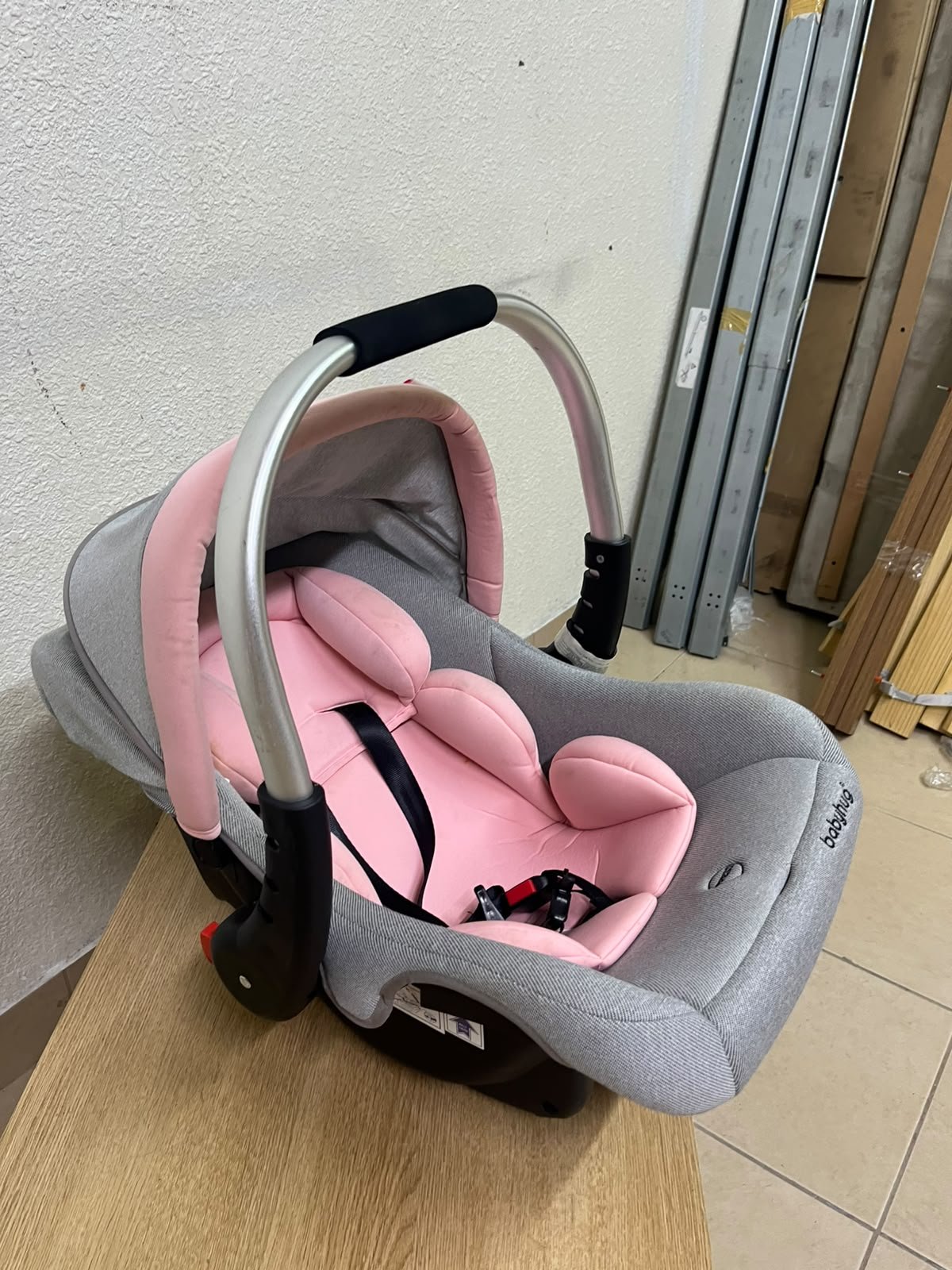 "Babyhug Onyx Elite" car seat and carrycot in grey and pink, featuring an aluminum handle.