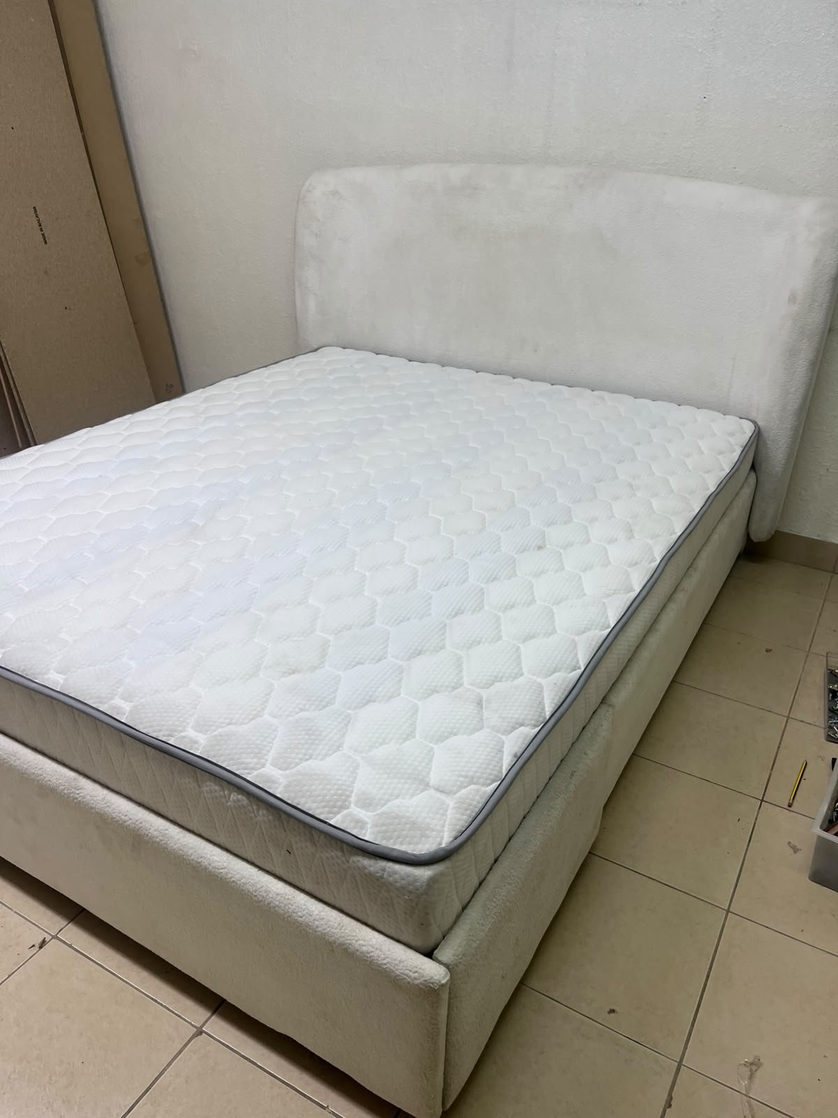 A modern, minimalist beige platform bed featuring a curved, upholstered headboard and a cushioned white mattress. - Image 2