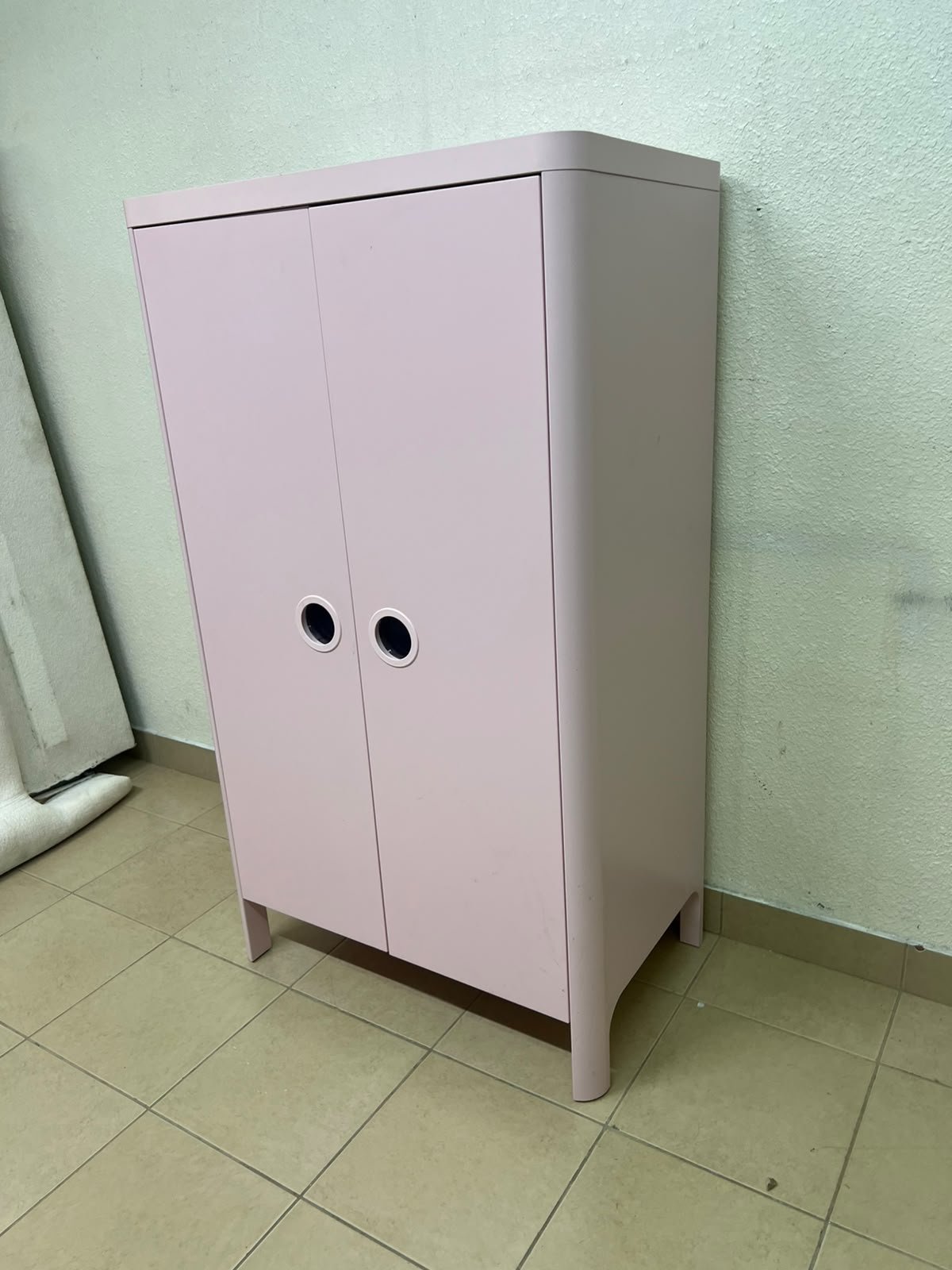 The "Busunge" children's wardrobe from IKEA comes in light pink and features rounded corners and distinctive circular cutouts that serve as handles.