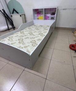 A white wooden single bed for children, featuring an integrated "dollhouse-style" headboard decorated with illustrations of miniature rooms.