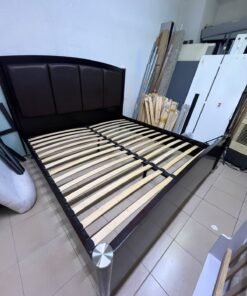 This dark wood platform bed features an arched, paneled headboard upholstered in faux leather, along with distinctive cylindrical corner legs accented with metallic silver-tone details. - Image 3