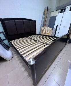 This dark wood platform bed features an arched, paneled headboard upholstered in faux leather, along with distinctive cylindrical corner legs accented with metallic silver-tone details. - Image 5