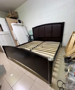 This dark wood platform bed features an arched, paneled headboard upholstered in faux leather, along with distinctive cylindrical corner legs accented with metallic silver-tone details. - Image 6