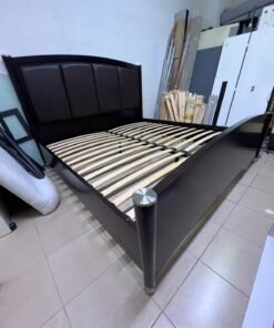 This dark wood platform bed features an arched, paneled headboard upholstered in faux leather, along with distinctive cylindrical corner legs accented with metallic silver-tone details.