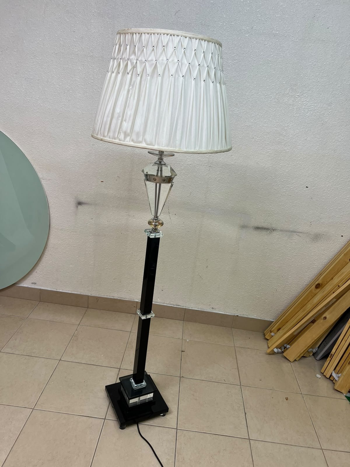 An elegant floor lamp combining crystal and black metal, featuring a conical, pleated fabric shade and a multi-faceted glass element positioned near the top of the lamp's stem. - Image 5