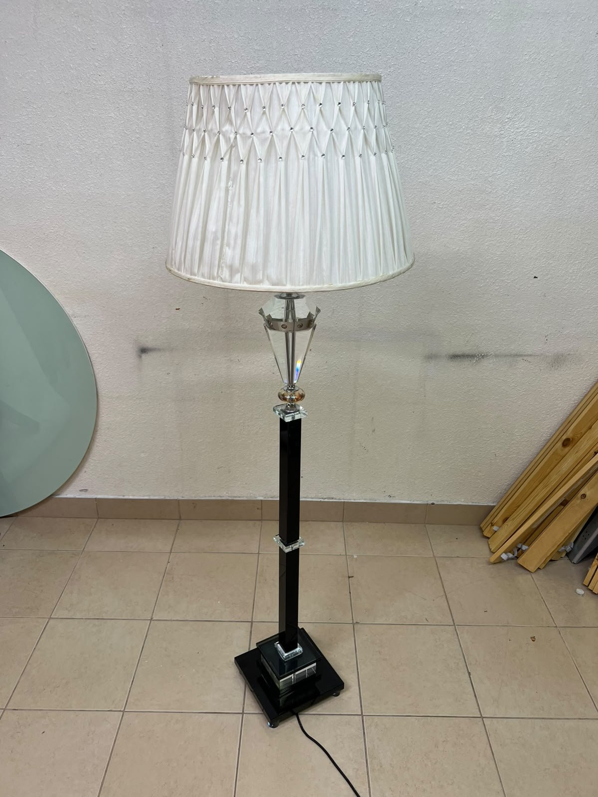 An elegant floor lamp combining crystal and black metal, featuring a conical, pleated fabric shade and a multi-faceted glass element positioned near the top of the lamp's stem. - Image 6