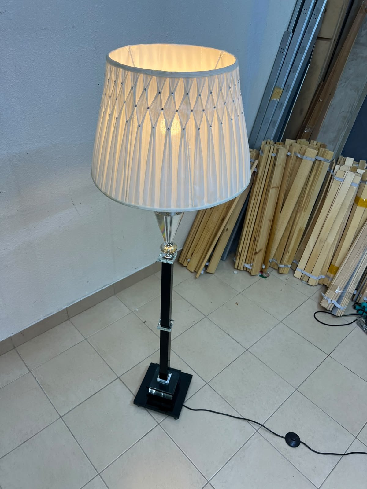 An elegant floor lamp combining crystal and black metal, featuring a conical, pleated fabric shade and a multi-faceted glass element positioned near the top of the lamp's stem. - Image 7