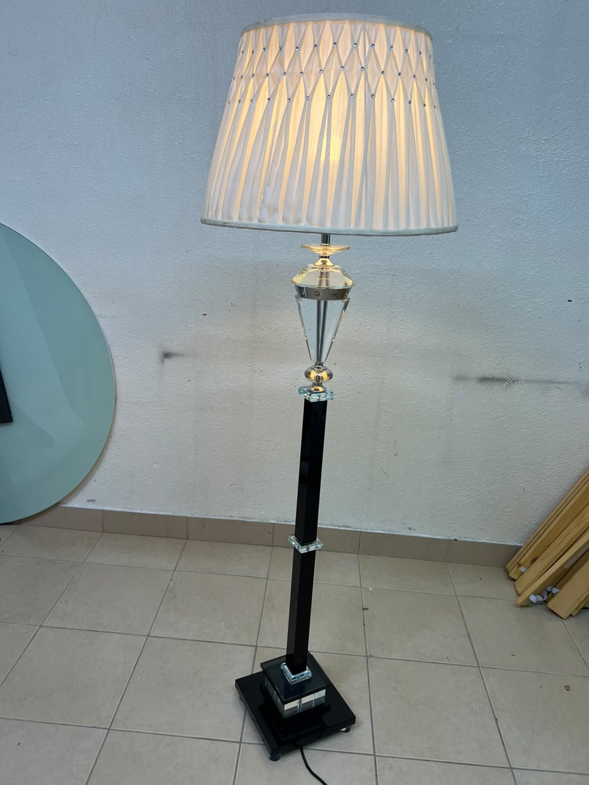 An elegant floor lamp combining crystal and black metal, featuring a conical, pleated fabric shade and a multi-faceted glass element positioned near the top of the lamp's stem. - Image 8