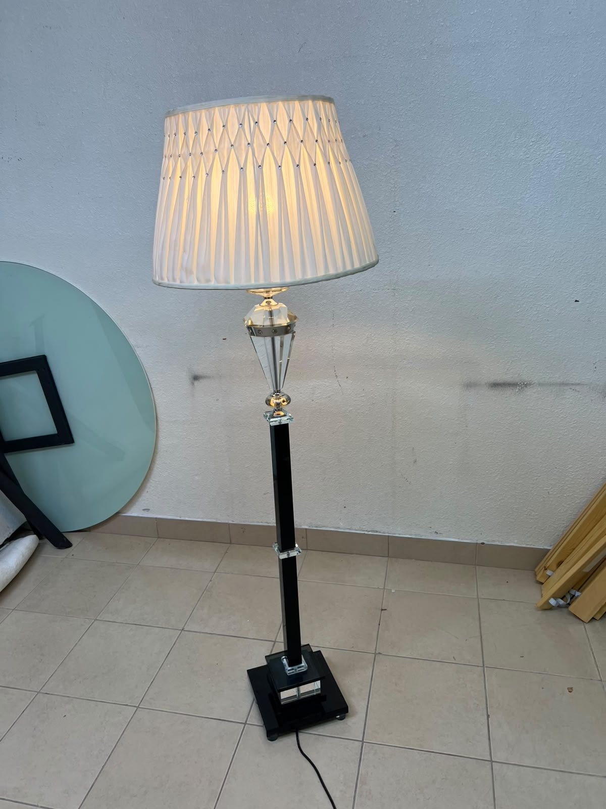 An elegant floor lamp combining crystal and black metal, featuring a conical, pleated fabric shade and a multi-faceted glass element positioned near the top of the lamp's stem. - Image 9
