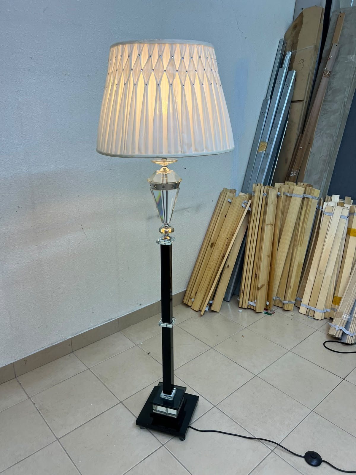An elegant floor lamp combining crystal and black metal, featuring a conical, pleated fabric shade and a multi-faceted glass element positioned near the top of the lamp's stem. - Image 2