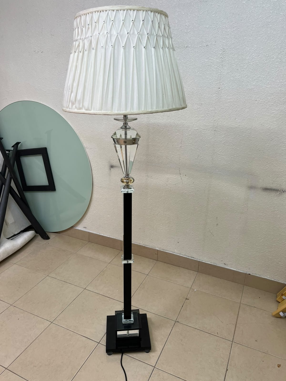 An elegant floor lamp combining crystal and black metal, featuring a conical, pleated fabric shade and a multi-faceted glass element positioned near the top of the lamp's stem. - Image 3