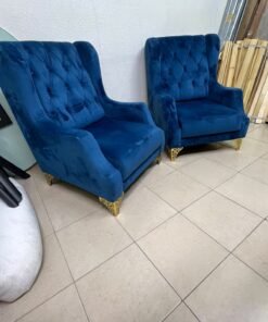 Wingback chairs upholstered in blue velvet, featuring ornate gold-finished metal legs.