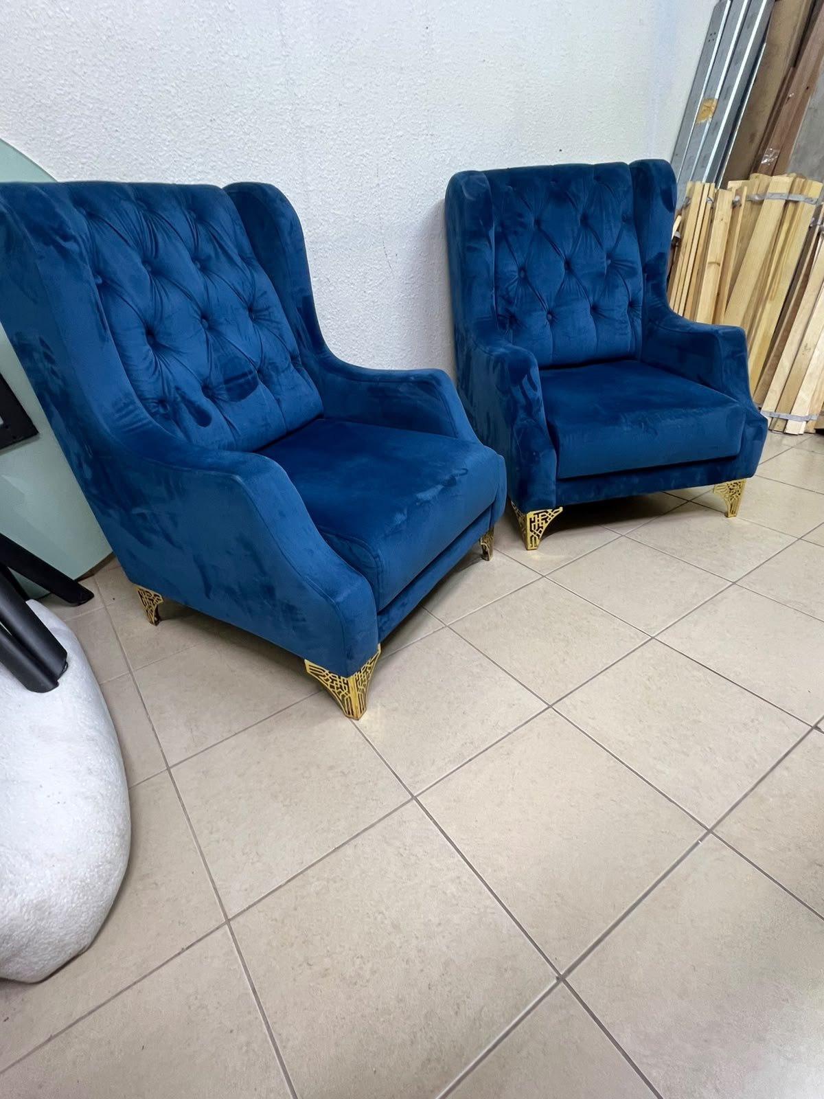 Wingback chairs upholstered in blue velvet, featuring ornate gold-finished metal legs.