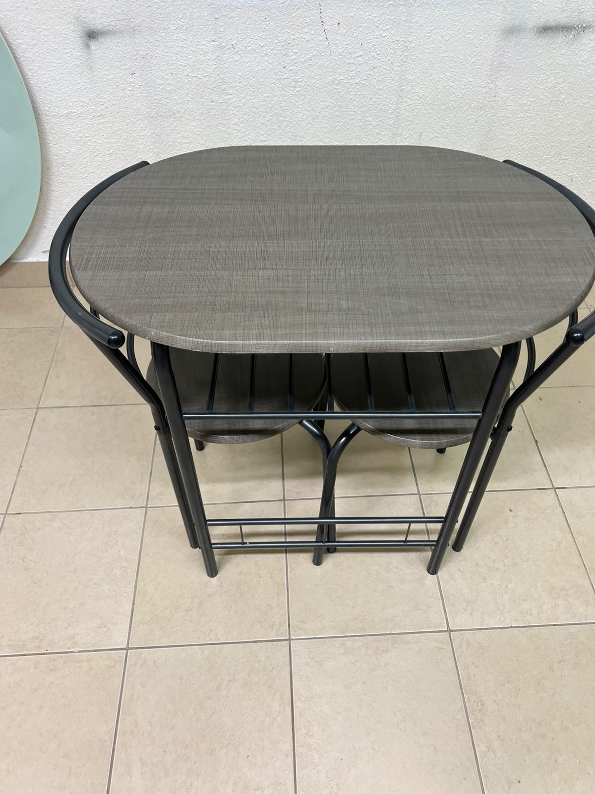 Two chairs and a table featuring an oval grey tabletop, a black tubular steel frame, and built-in storage shelves. - Image 6