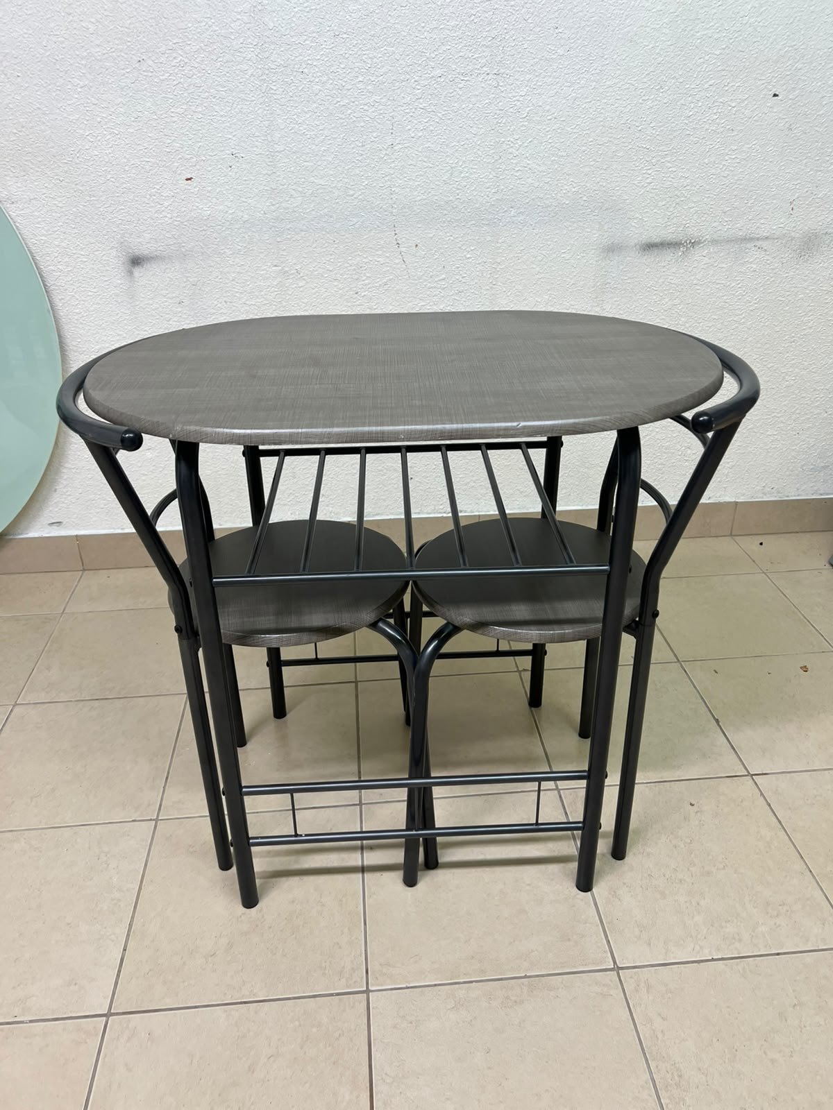 Two chairs and a table featuring an oval grey tabletop, a black tubular steel frame, and built-in storage shelves. - Image 7