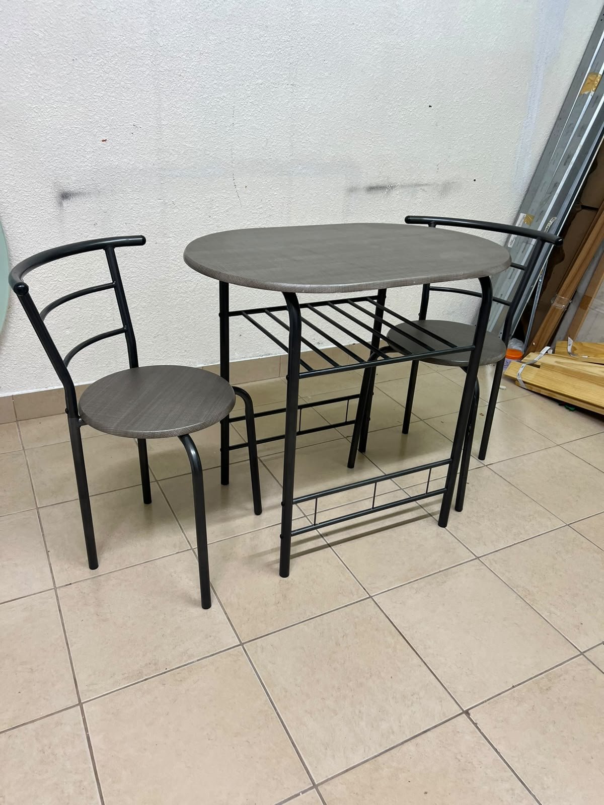Two chairs and a table featuring an oval grey tabletop, a black tubular steel frame, and built-in storage shelves. - Image 9
