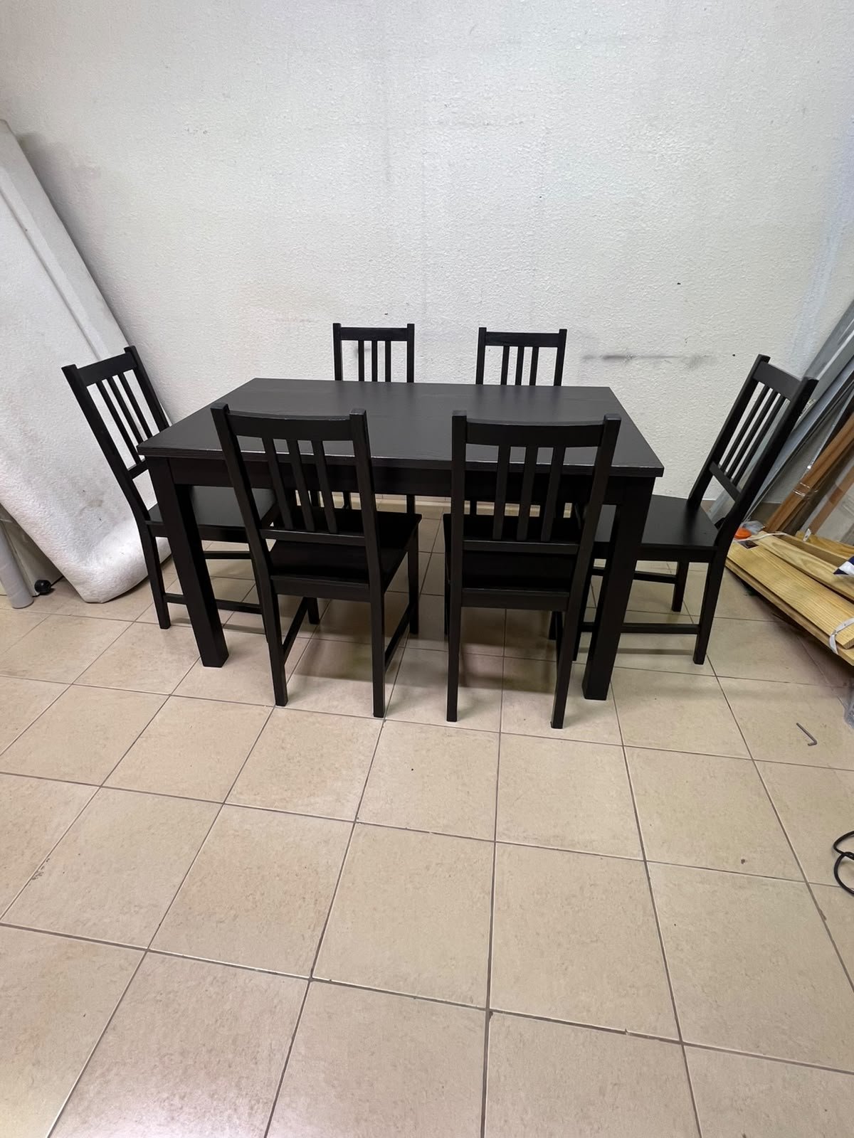 A dark solid wood dining table with matching slat-back chairs, featuring the design of the "Nordviken" collection from IKEA.