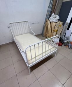 The white extendable metal bed frame "MINNEN" from IKEA, featuring side rails with distinctive scrollwork details.