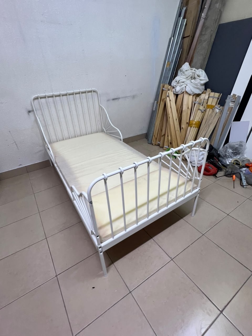 The white extendable metal bed frame "MINNEN" from IKEA, featuring side rails with distinctive scrollwork details.