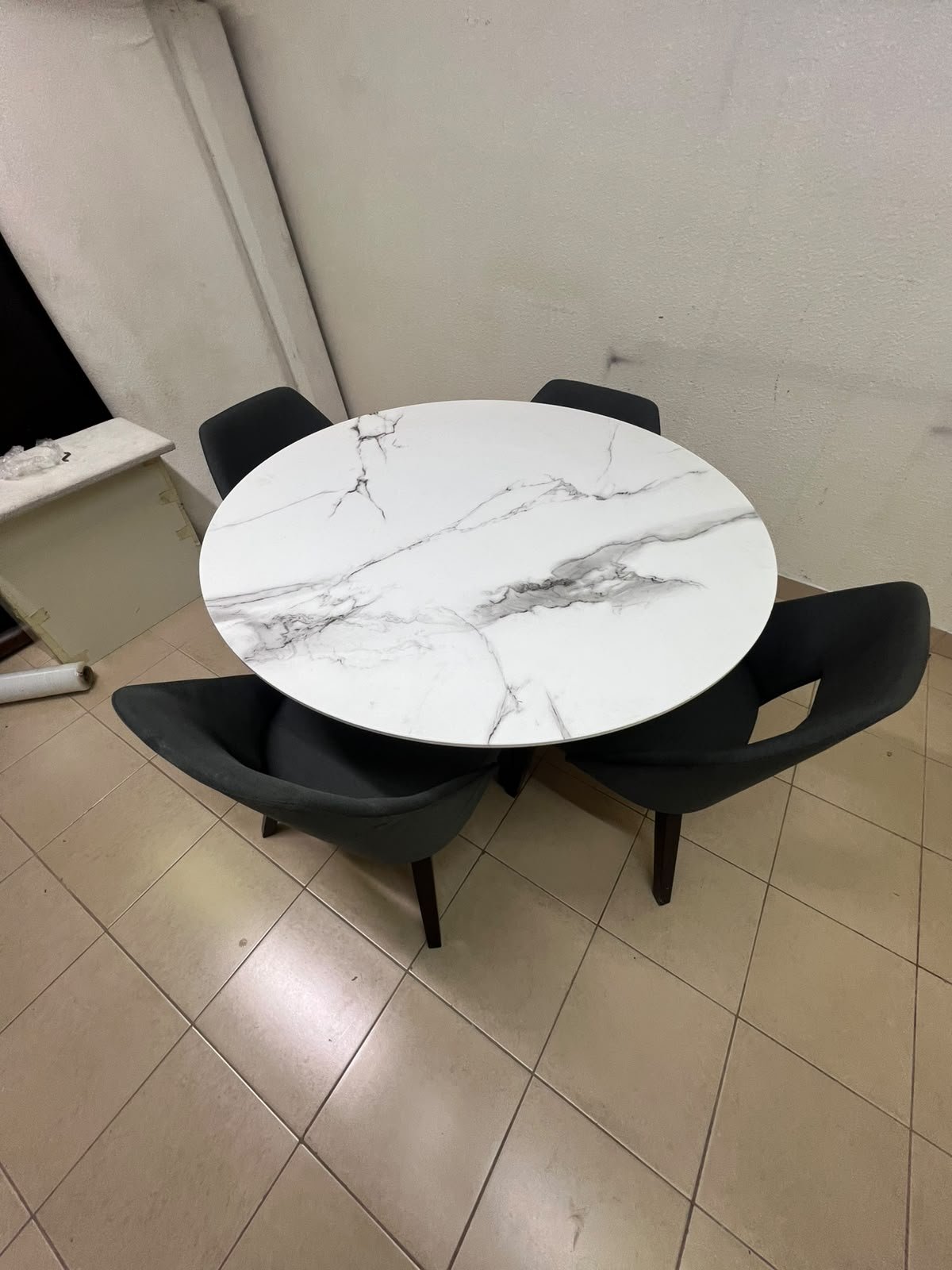 This modern dining set features a round table with a white marble-effect top, paired with curved, arm-equipped chairs upholstered in dark gray and supported by black metal legs. - Image 2