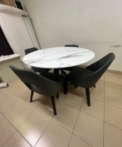 This modern dining set features a round table with a white marble-effect top, paired with curved, arm-equipped chairs upholstered in dark gray and supported by black metal legs. - Image 3