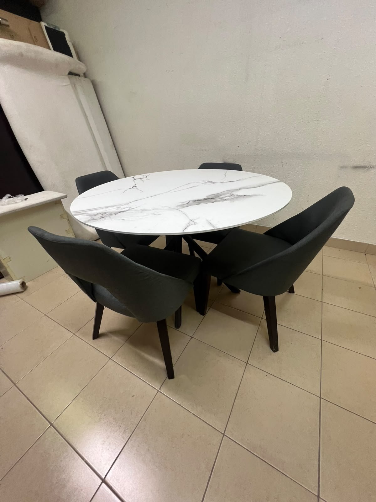 This modern dining set features a round table with a white marble-effect top, paired with curved, arm-equipped chairs upholstered in dark gray and supported by black metal legs. - Image 3