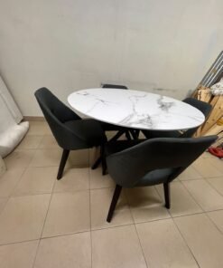 This modern dining set features a round table with a white marble-effect top, paired with curved, arm-equipped chairs upholstered in dark gray and supported by black metal legs. - Image 4