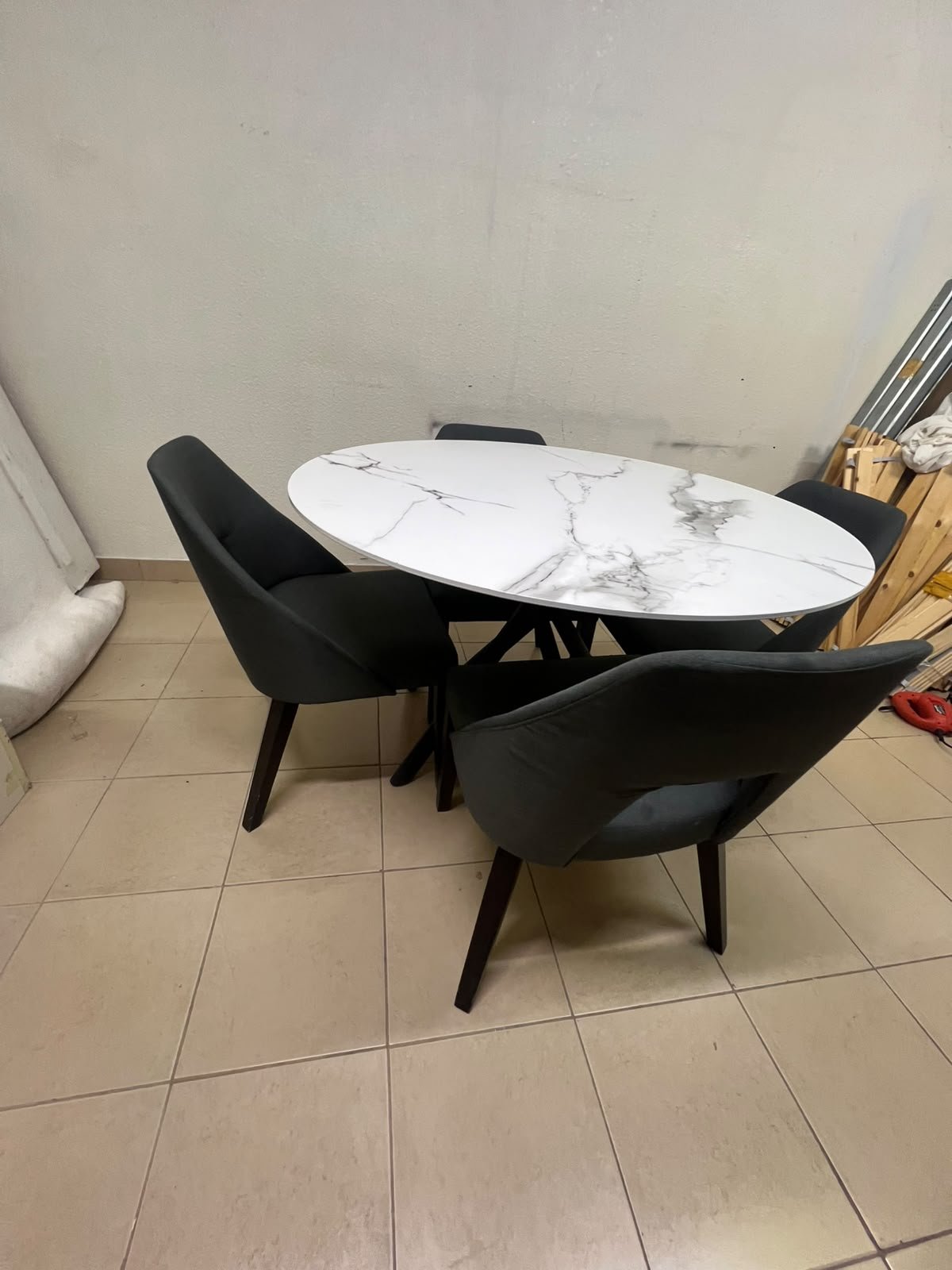 This modern dining set features a round table with a white marble-effect top, paired with curved, arm-equipped chairs upholstered in dark gray and supported by black metal legs. - Image 4