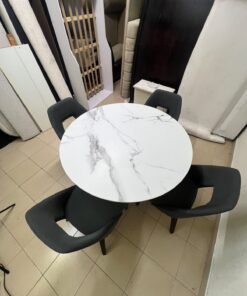 This modern dining set features a round table with a white marble-effect top, paired with curved, arm-equipped chairs upholstered in dark gray and supported by black metal legs. - Image 5