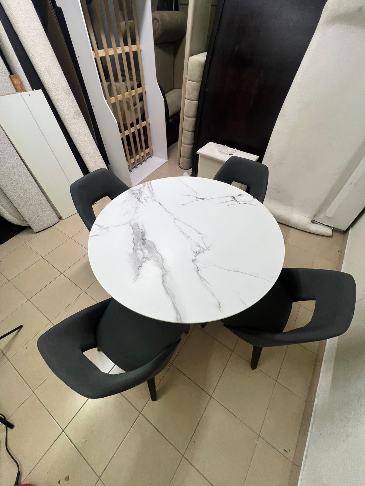 This modern dining set features a round table with a white marble-effect top, paired with curved, arm-equipped chairs upholstered in dark gray and supported by black metal legs. - Image 5