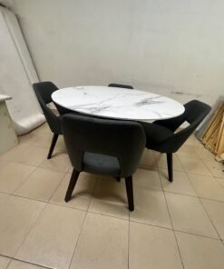 This modern dining set features a round table with a white marble-effect top, paired with curved, arm-equipped chairs upholstered in dark gray and supported by black metal legs. - Image 6
