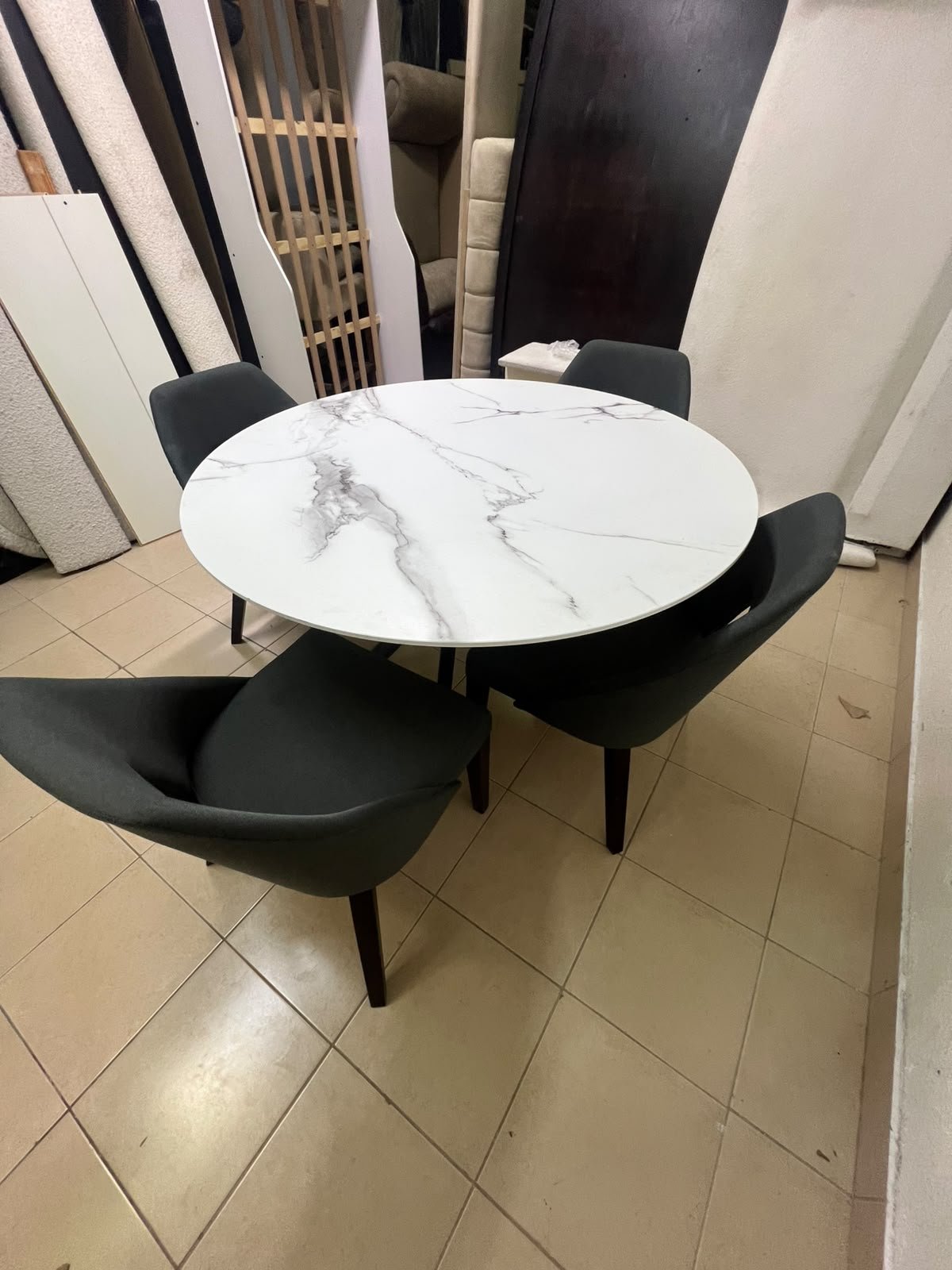 This modern dining set features a round table with a white marble-effect top, paired with curved, arm-equipped chairs upholstered in dark gray and supported by black metal legs. - Image 11