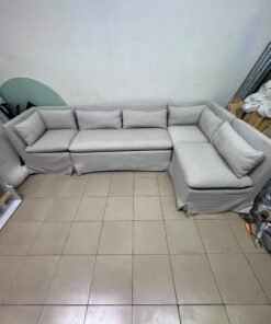 The L-shaped sectional sofa features a removable cover; it is the Crate & Barrel Belmar Modular Seating model, upholstered in a light gray, high-performance fabric with a linen-like texture, and includes comfortable back and arm cushions.