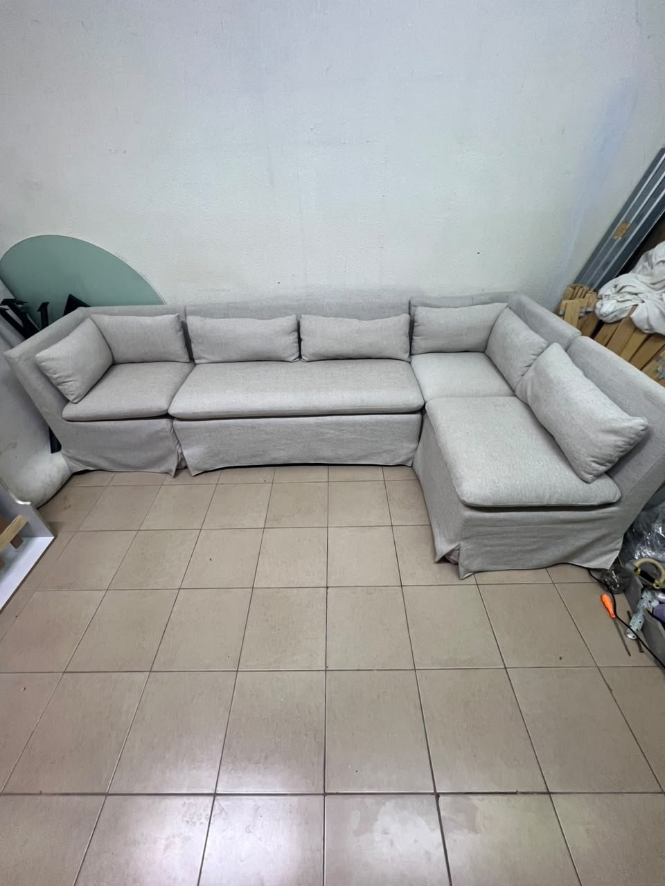 The L-shaped sectional sofa features a removable cover; it is the Crate & Barrel Belmar Modular Seating model, upholstered in a light gray, high-performance fabric with a linen-like texture, and includes comfortable back and arm cushions.