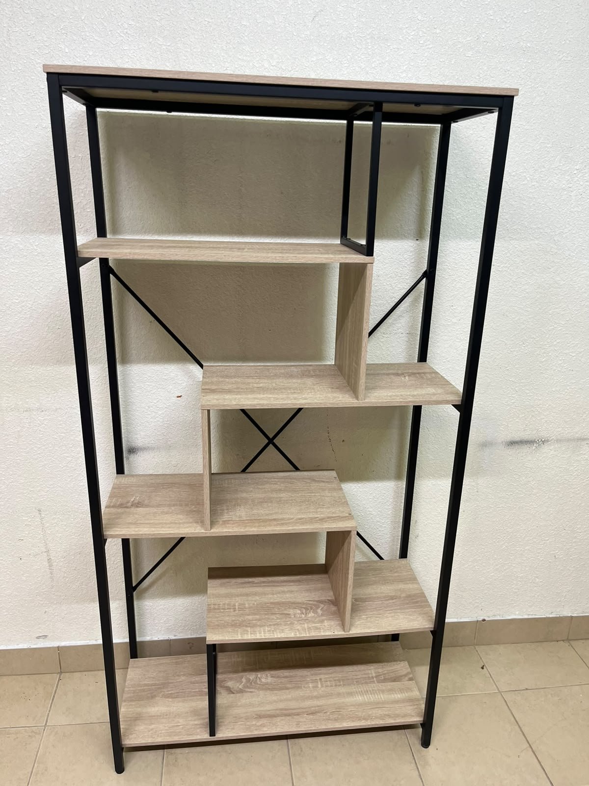 A shelving unit featuring a modern industrial design, consisting of a sturdy black metal frame and natural-look wooden shelves arranged in a tiered, graduated-width layout.