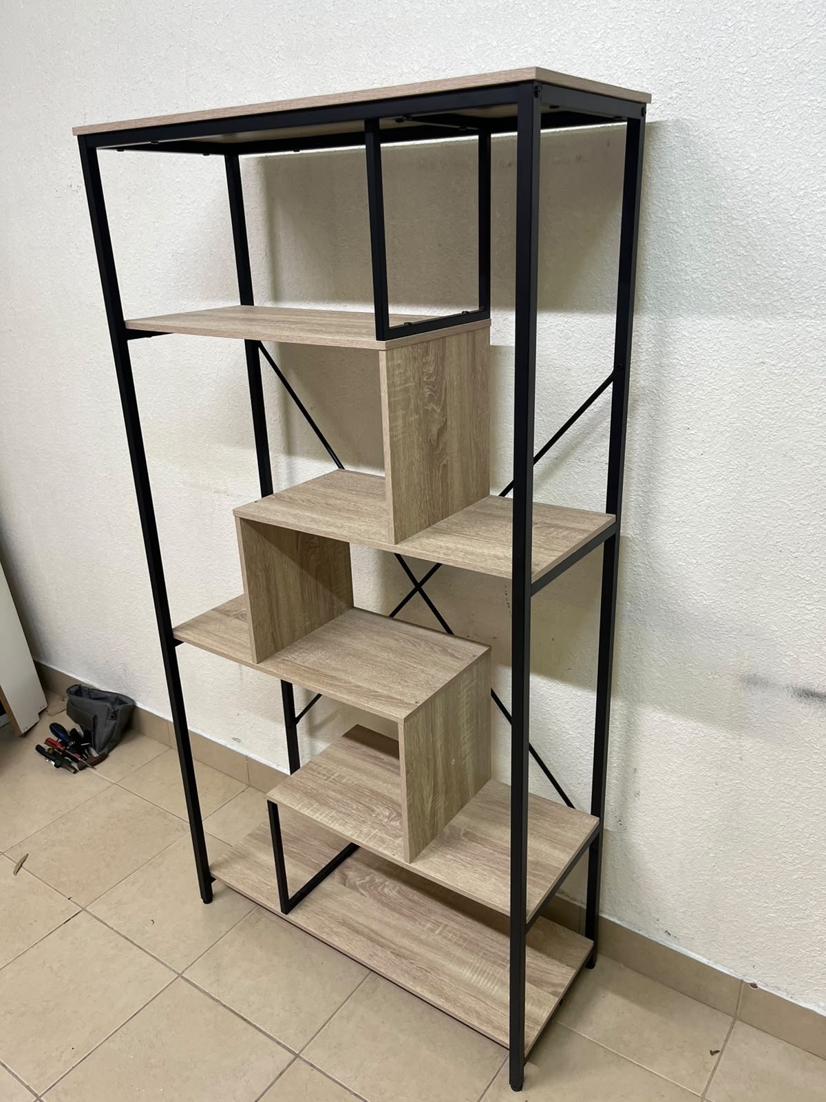 A shelving unit featuring a modern industrial design, consisting of a sturdy black metal frame and natural-look wooden shelves arranged in a tiered, graduated-width layout. - Image 11