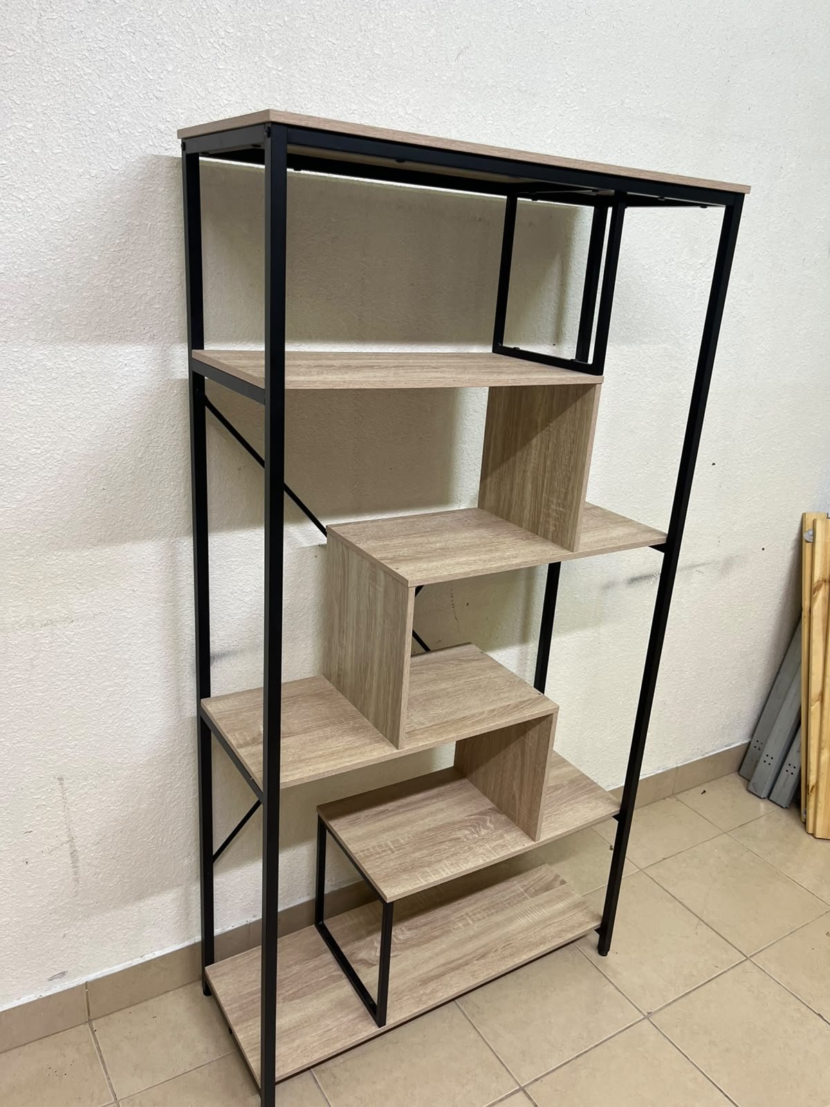 A shelving unit featuring a modern industrial design, consisting of a sturdy black metal frame and natural-look wooden shelves arranged in a tiered, graduated-width layout. - Image 2