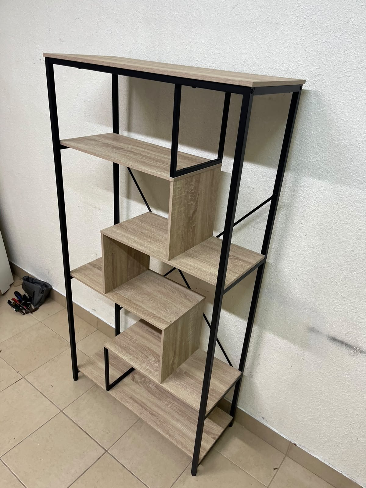 A shelving unit featuring a modern industrial design, consisting of a sturdy black metal frame and natural-look wooden shelves arranged in a tiered, graduated-width layout. - Image 6