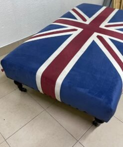 An Ottoman upholstered in luxurious velvet, featuring a vintage British flag design and metal stud detailing along the sides. - Image 2