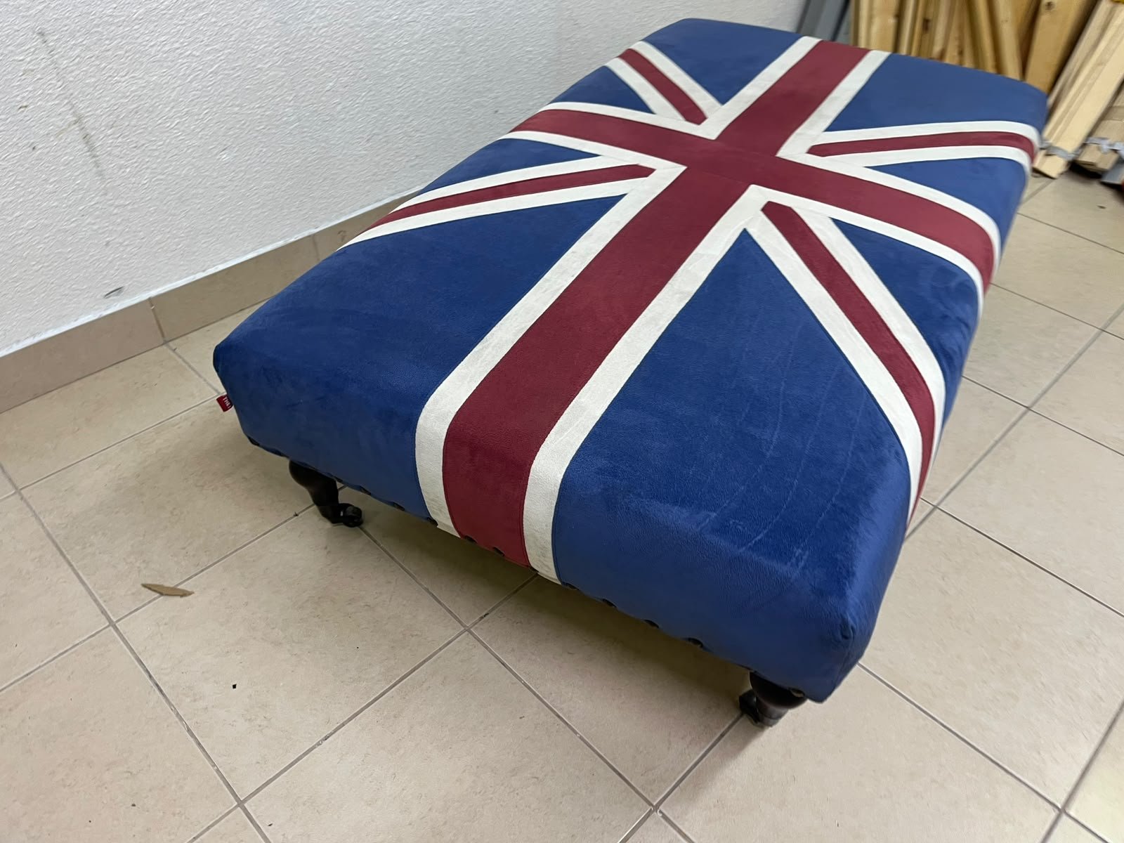 An Ottoman upholstered in luxurious velvet, featuring a vintage British flag design and metal stud detailing along the sides. - Image 2