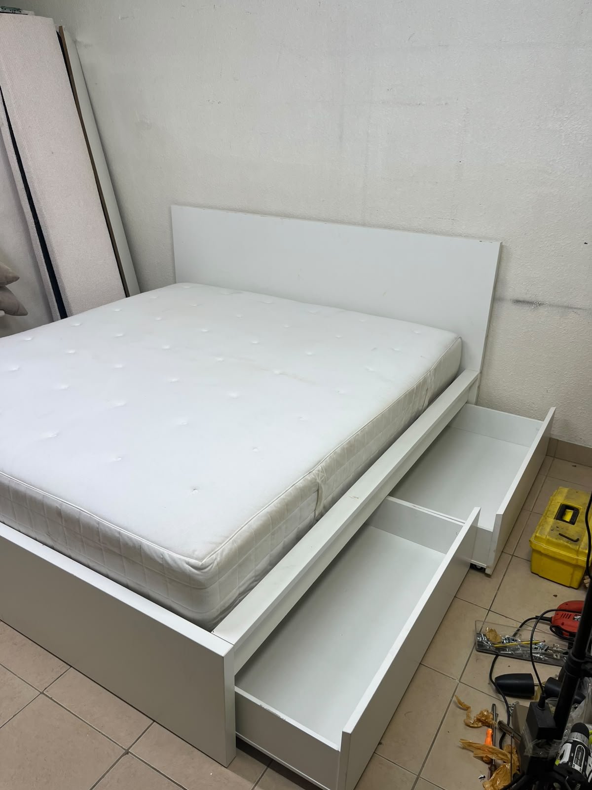 The bed is the high-frame MALM model from IKEA, featuring a white finish and practical under-bed drawers for storing bedding and clothing.