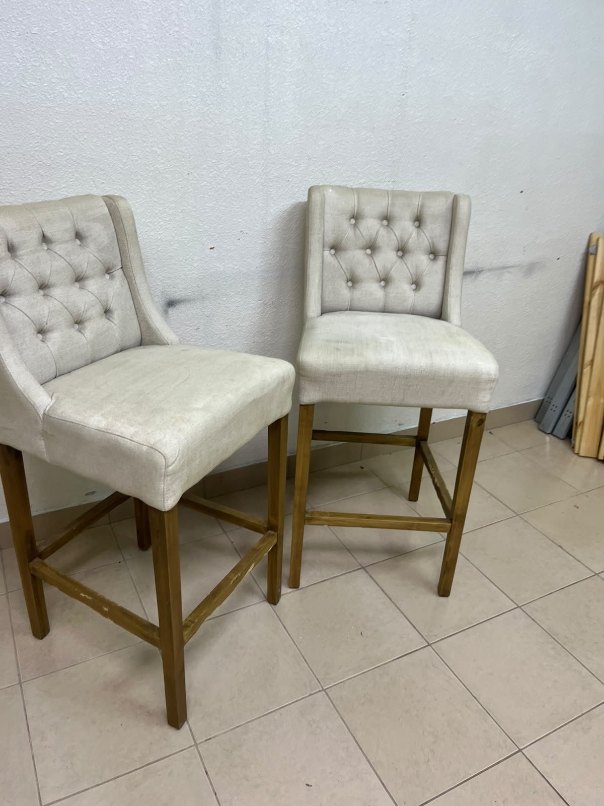 A pair of bar stools featuring a wingback design, beige fabric upholstery with button tufting, and wooden legs. - Image 4