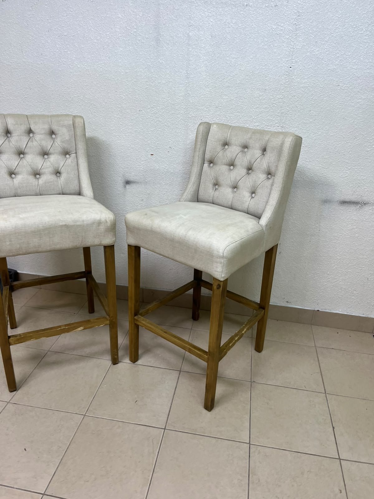 A pair of bar stools featuring a wingback design, beige fabric upholstery with button tufting, and wooden legs. - Image 8