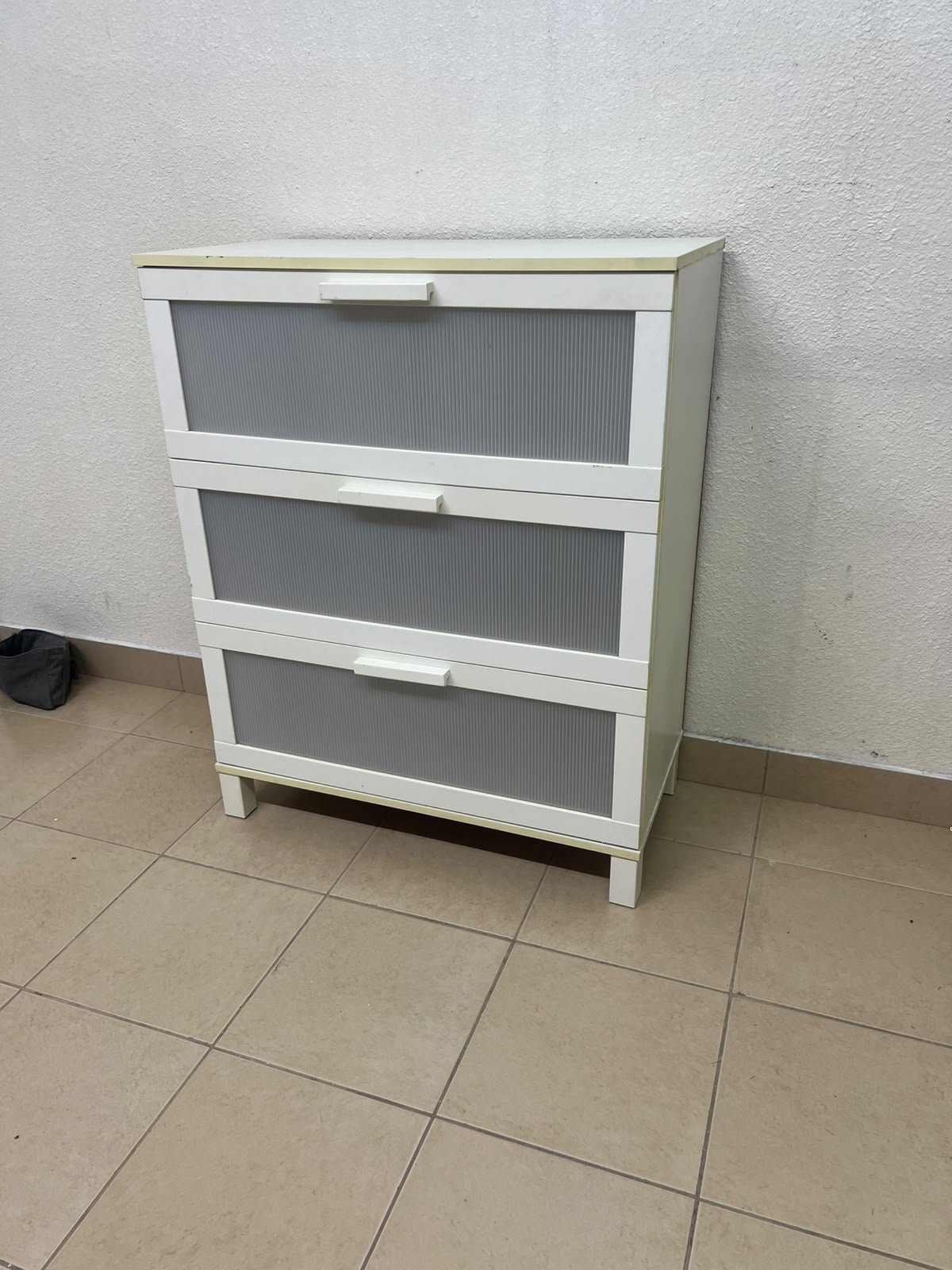 A white three-drawer chest with grey striped drawer fronts, similar to the IKEA Aneboda.