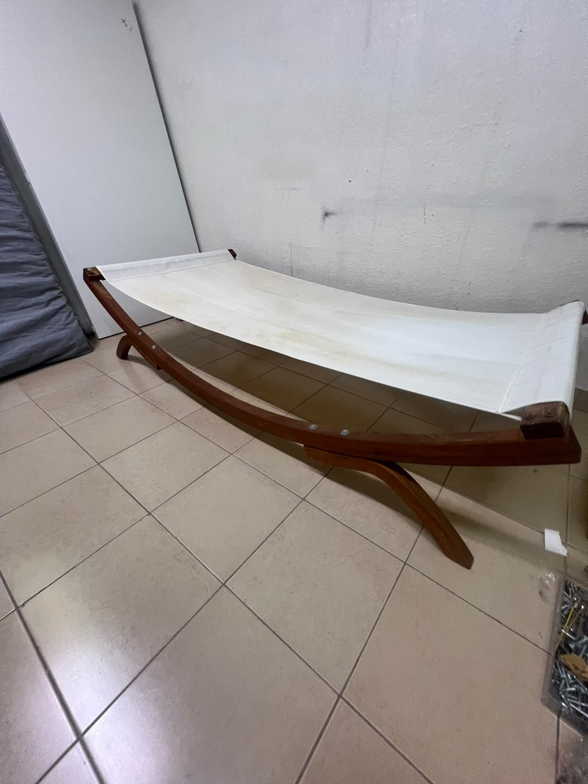 An elegantly designed, curved wooden hammock bed featuring comfortable white fabric for relaxation.