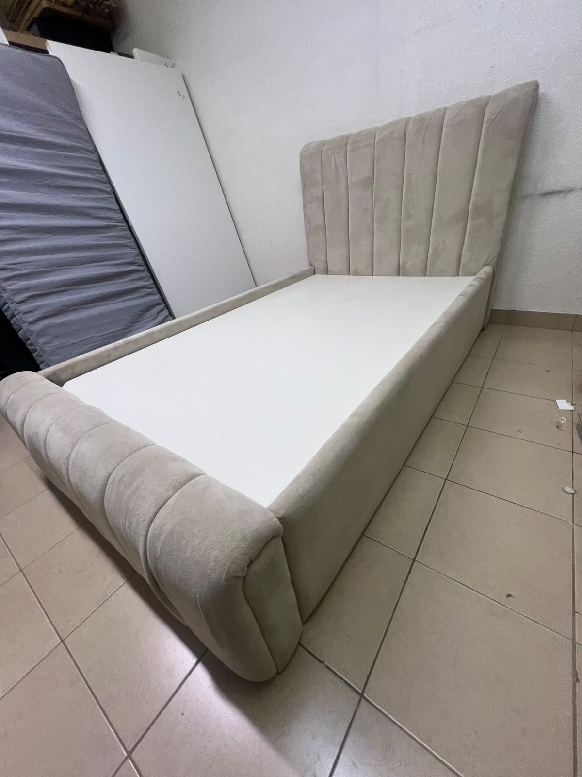 An elegantly designed, modern upholstered bed featuring a high headboard padded with prominent vertical lines and a curved footboard. - Image 3