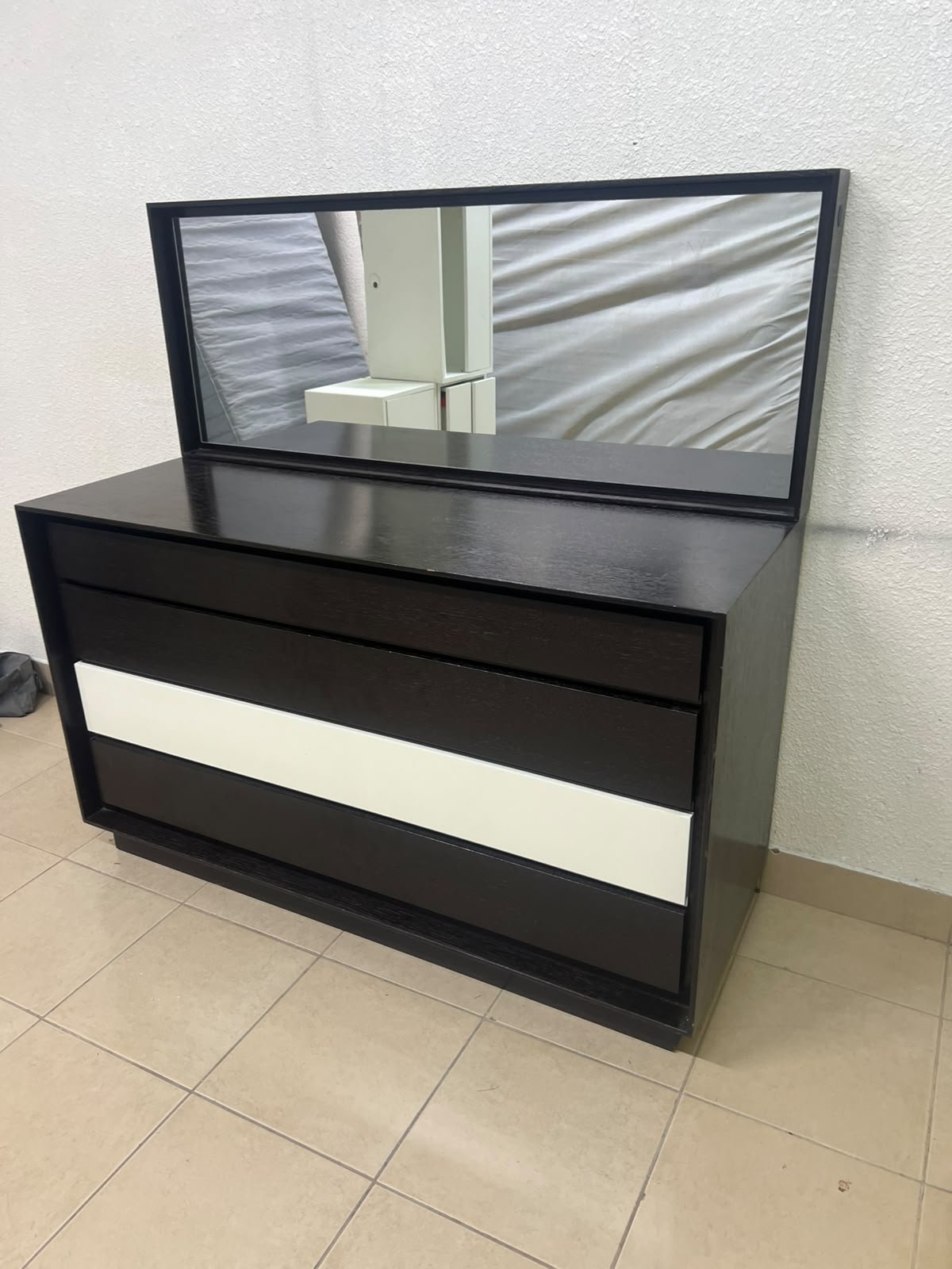 A dark brown wooden dresser featuring a wide white central drawer, accompanied by a large mirror with a matching rectangular frame.