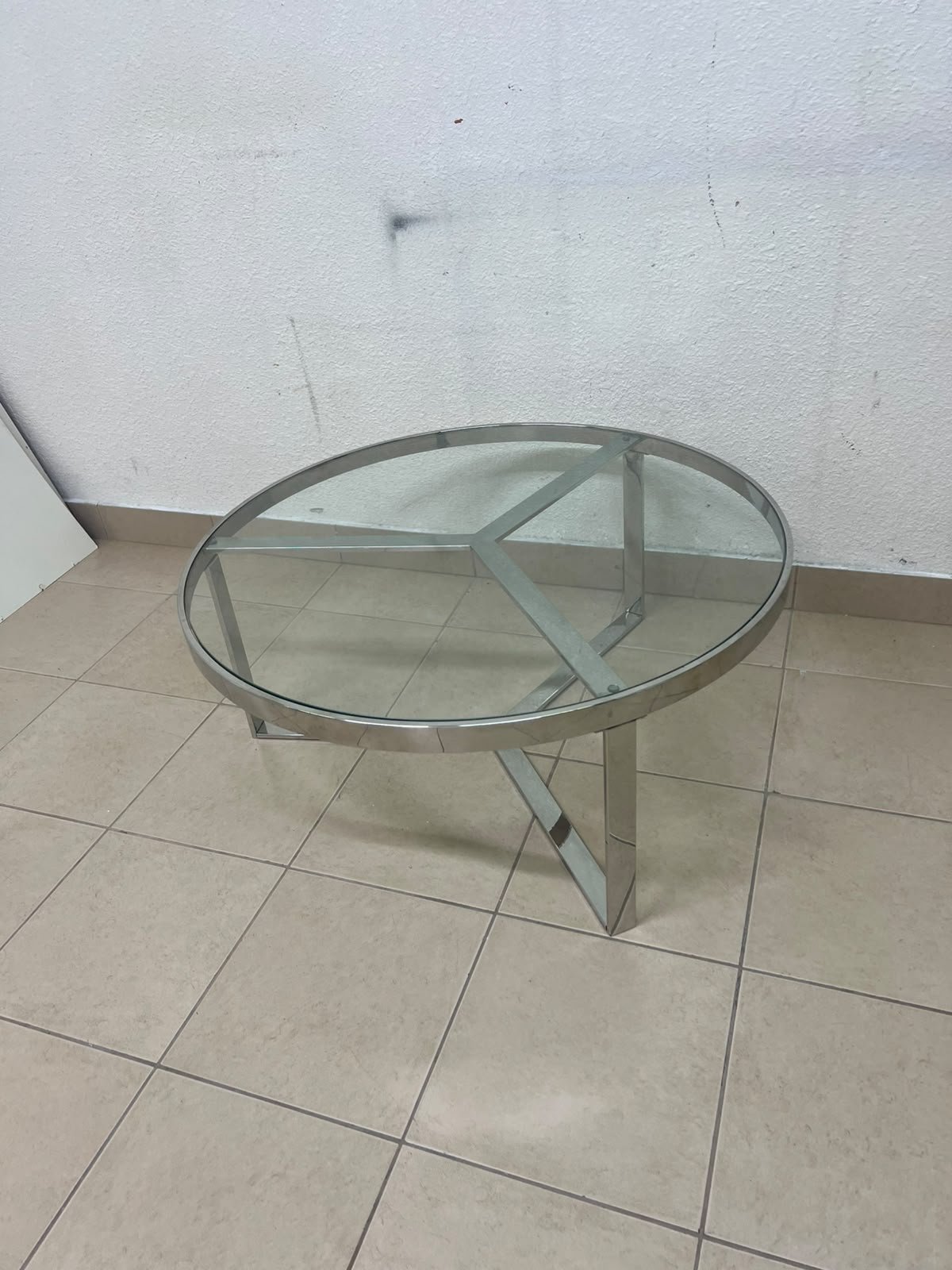 A round coffee table featuring a silver-colored metal frame (steel or chrome), a clear glass top, and a geometric crisscross base design. - Image 2